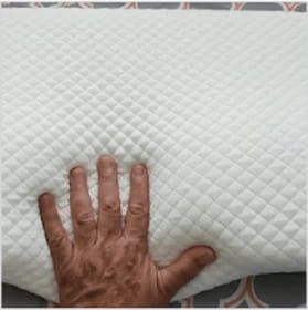 Hand pressing down on a textured white fabric, showcasing its softness.